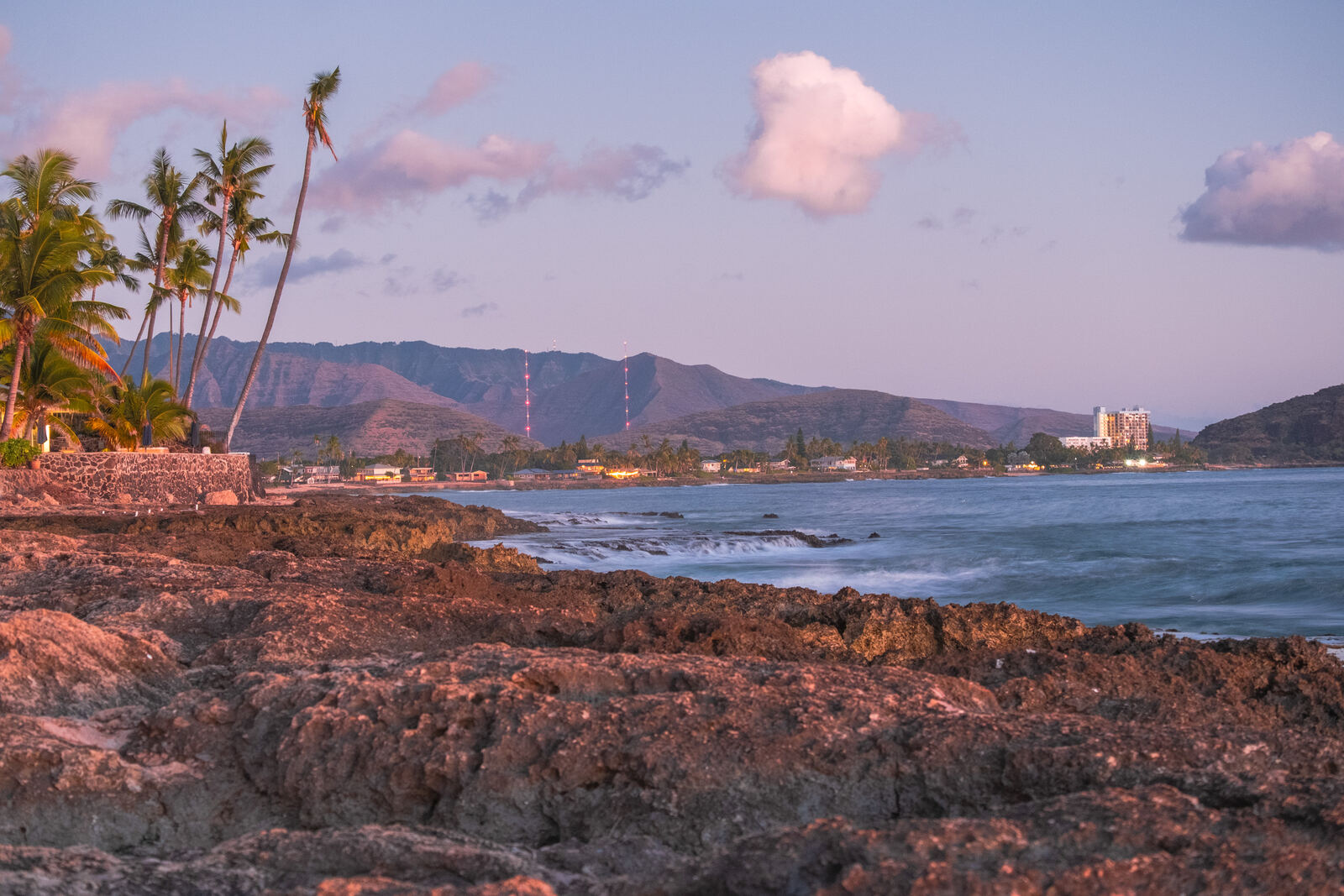 Rocky coastline and town at pink dusk