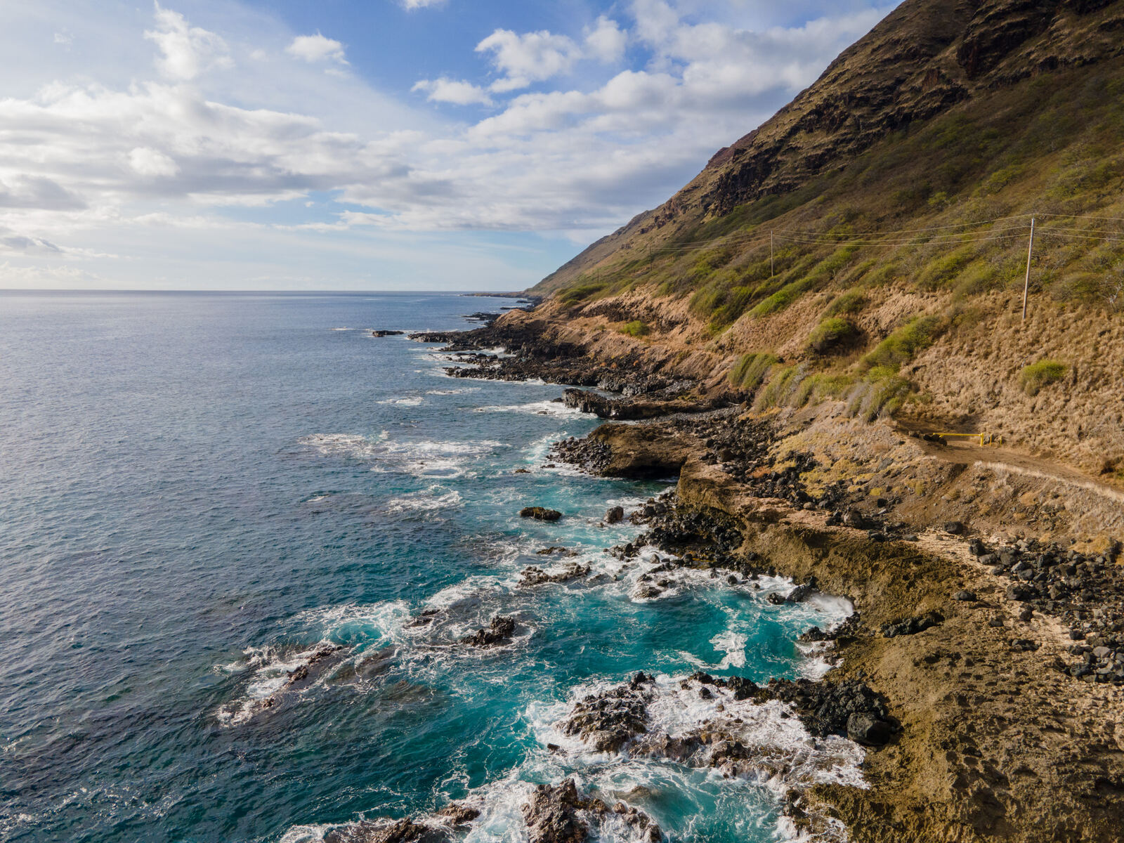 Aerial of turquoise surf against a cliffside coast