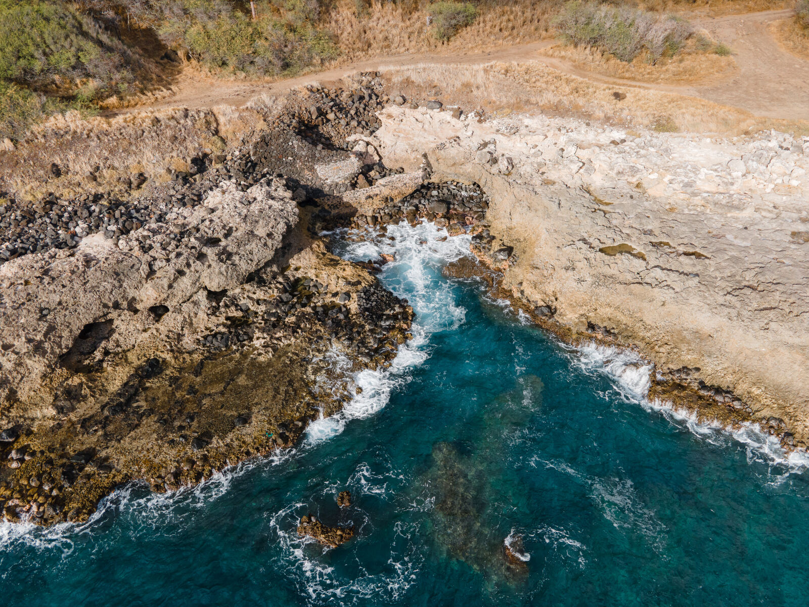 Top-down aerial of a turquoise rock cove