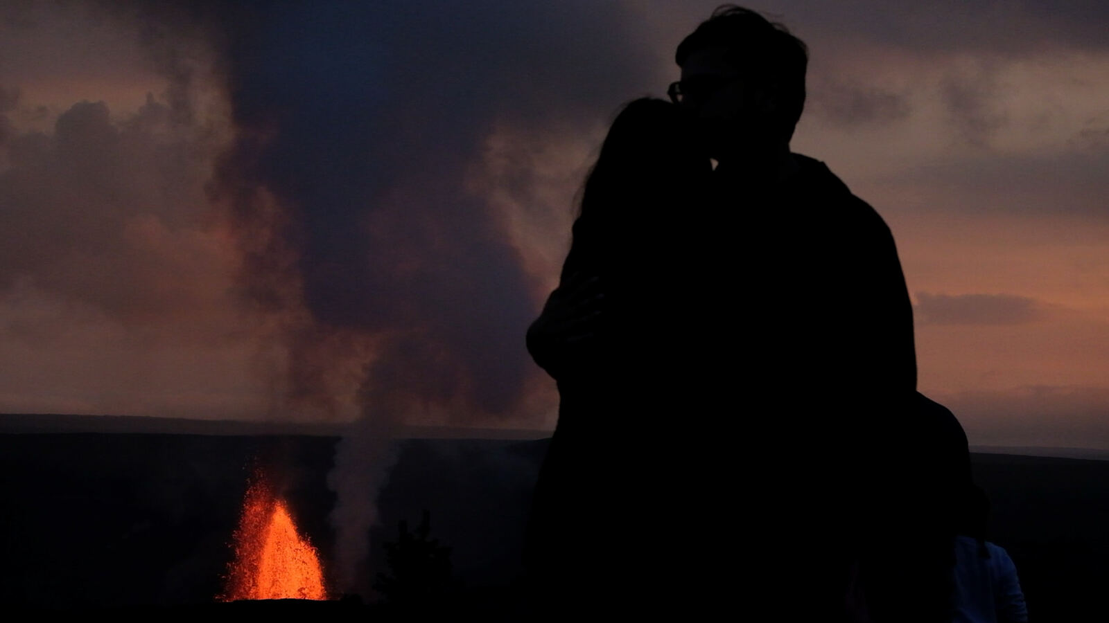 Silhouetted couple before an erupting Kilauea vent at dusk
