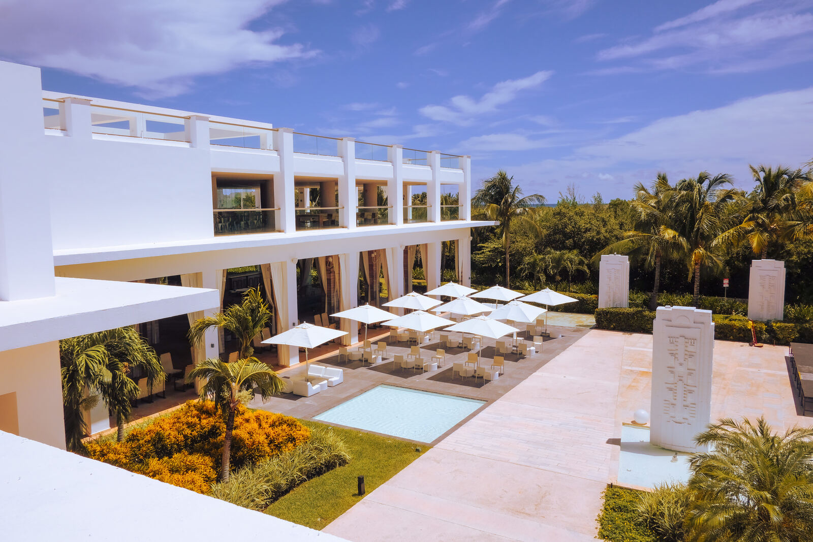 Modern white resort courtyard with pool and umbrellas