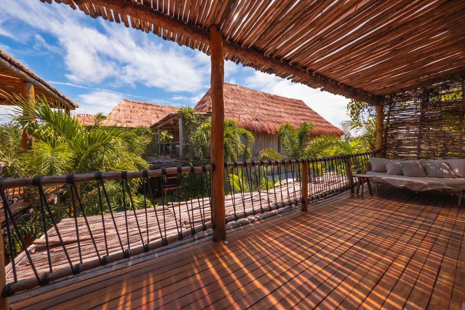 Shaded pergola deck with rope railings and thatched roofs